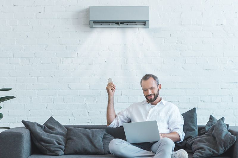 Image of someone sitting below a ductless system. Video - 4 Amazing Benefits of Ductless Units.